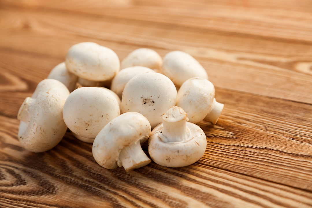 Button mushrooms on wooden board | Featured image for wholesale mushrooms.